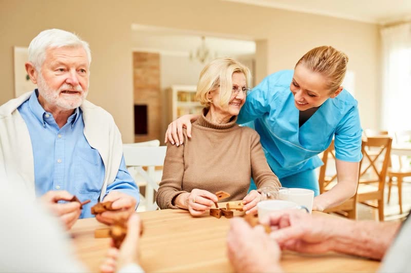 A live-in carer helping an elderly couple at home